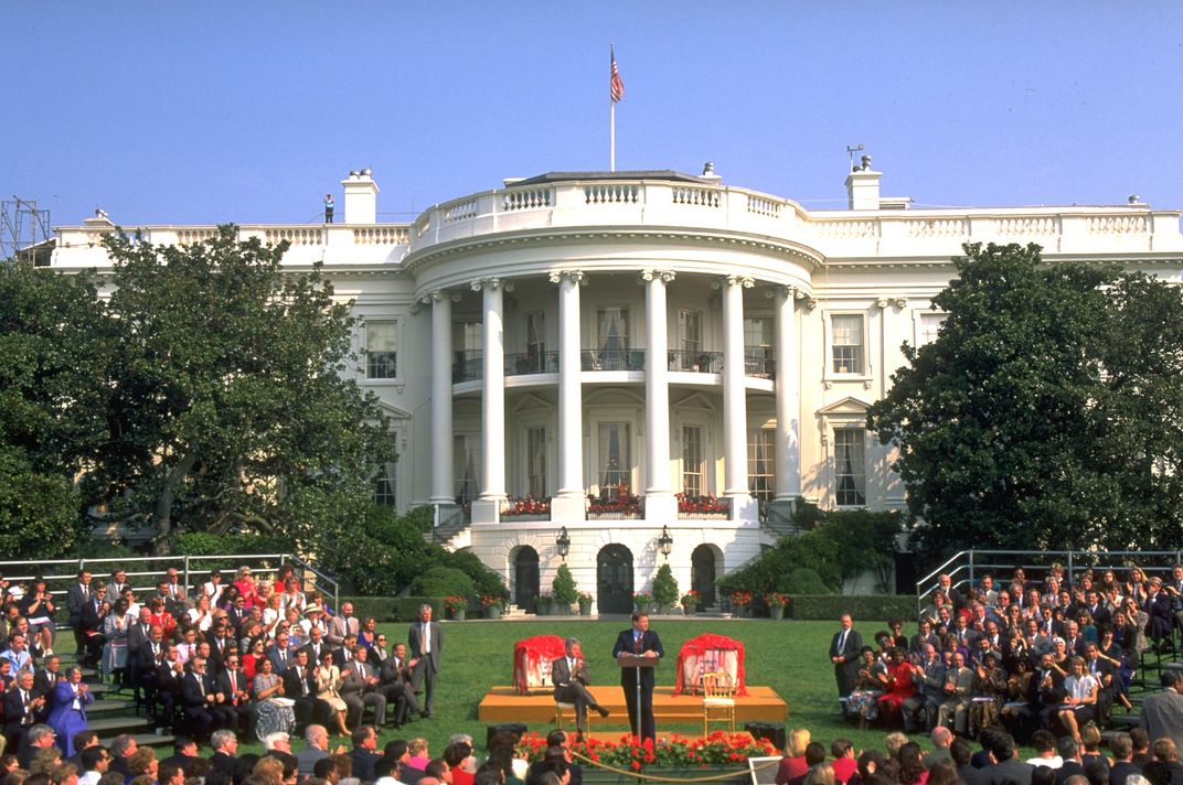 Clinton (seated on stage) attends an event in front of the White House in 1994.